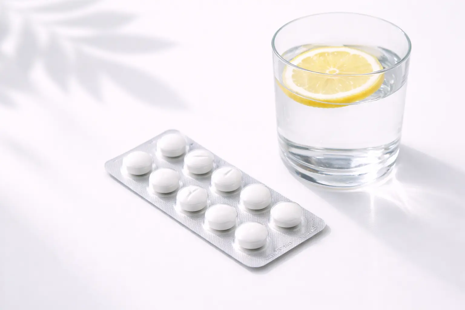 A minimalist flat-lay of pain relief medication and a glass of water, representing period pain management
