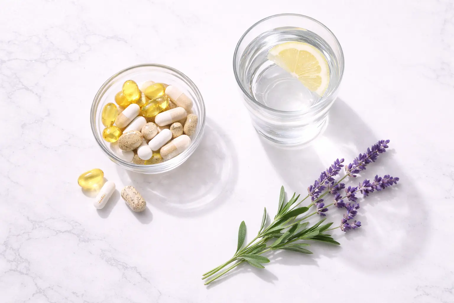 A minimalist flat-lay of wellness supplements and water, representing holistic management of pre-menstrual syndrome