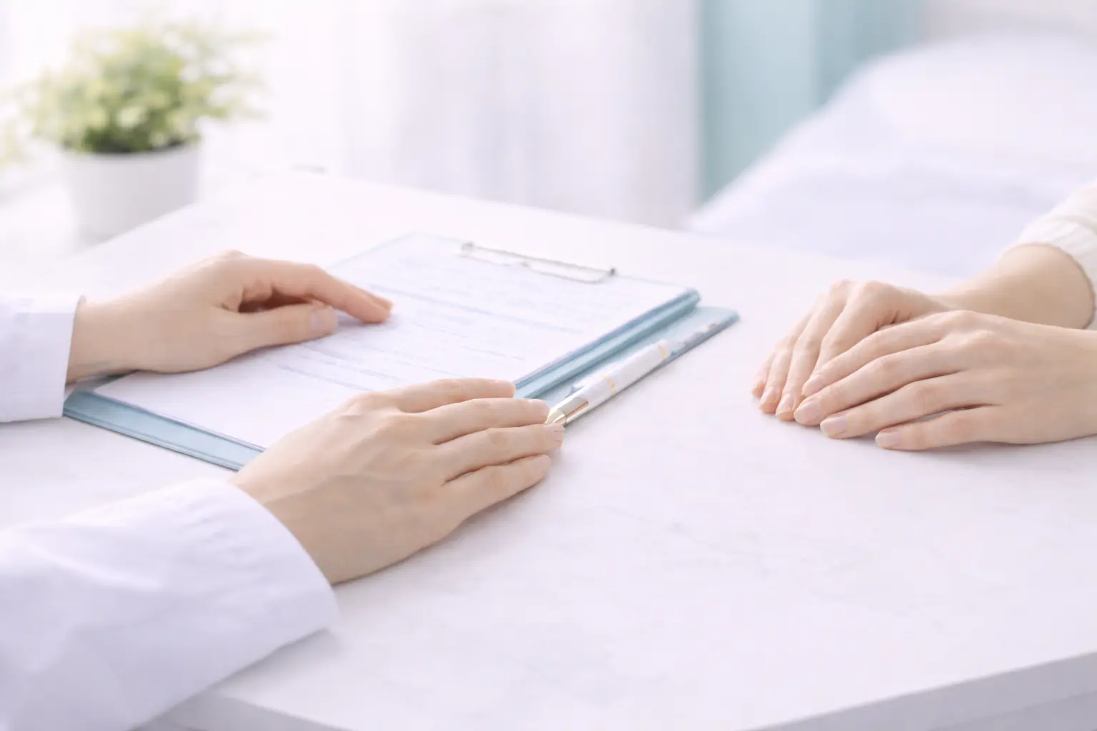 Close-up of a specialist's hands and a patient's hands reviewing a medical chart during an implant removal consultation