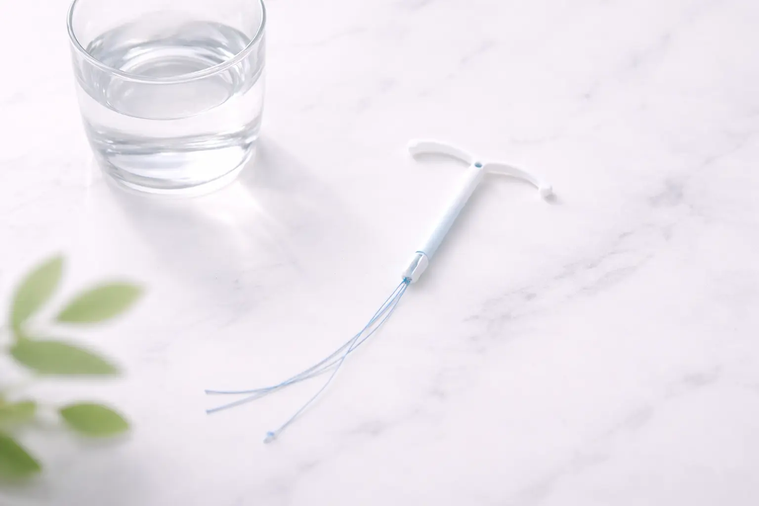 A high-end medical flat-lay showing a T-shaped intrauterine device (IUD) on a clean, professional surface